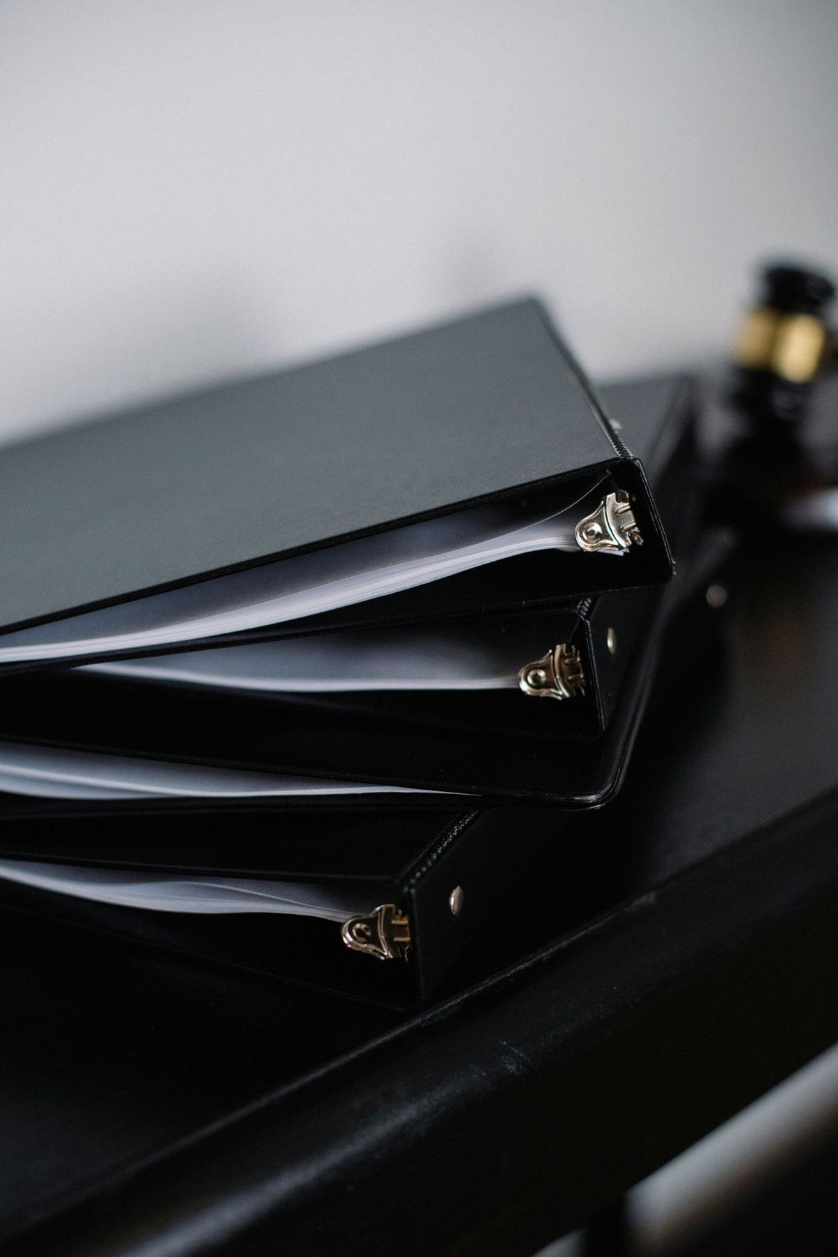 Black ring binders lined up on a dark shelf