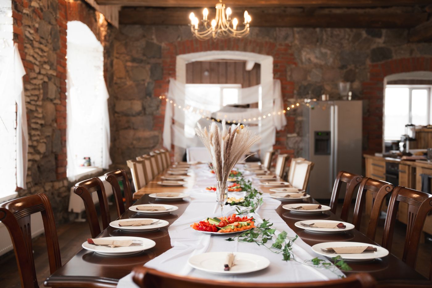 A long dressed table in a stone-walled room under a chandelier