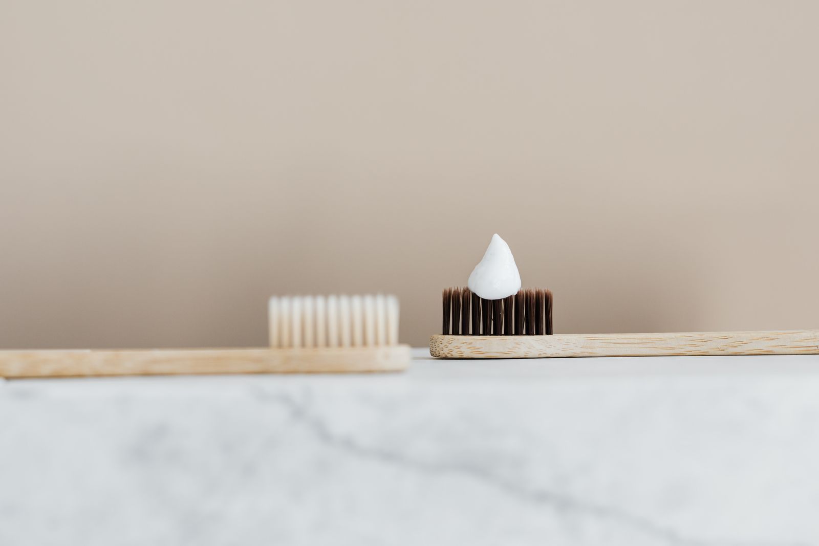 Two bamboo toothbrushes resting on a pale marble ledge