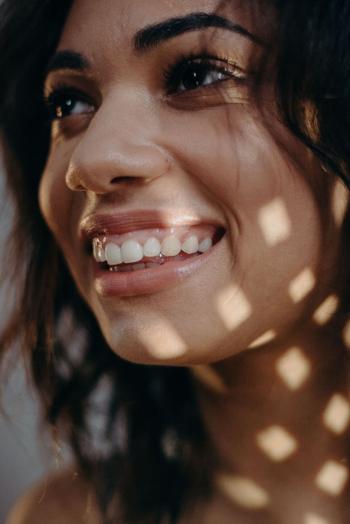 A woman smiling in warm, dappled afternoon light
