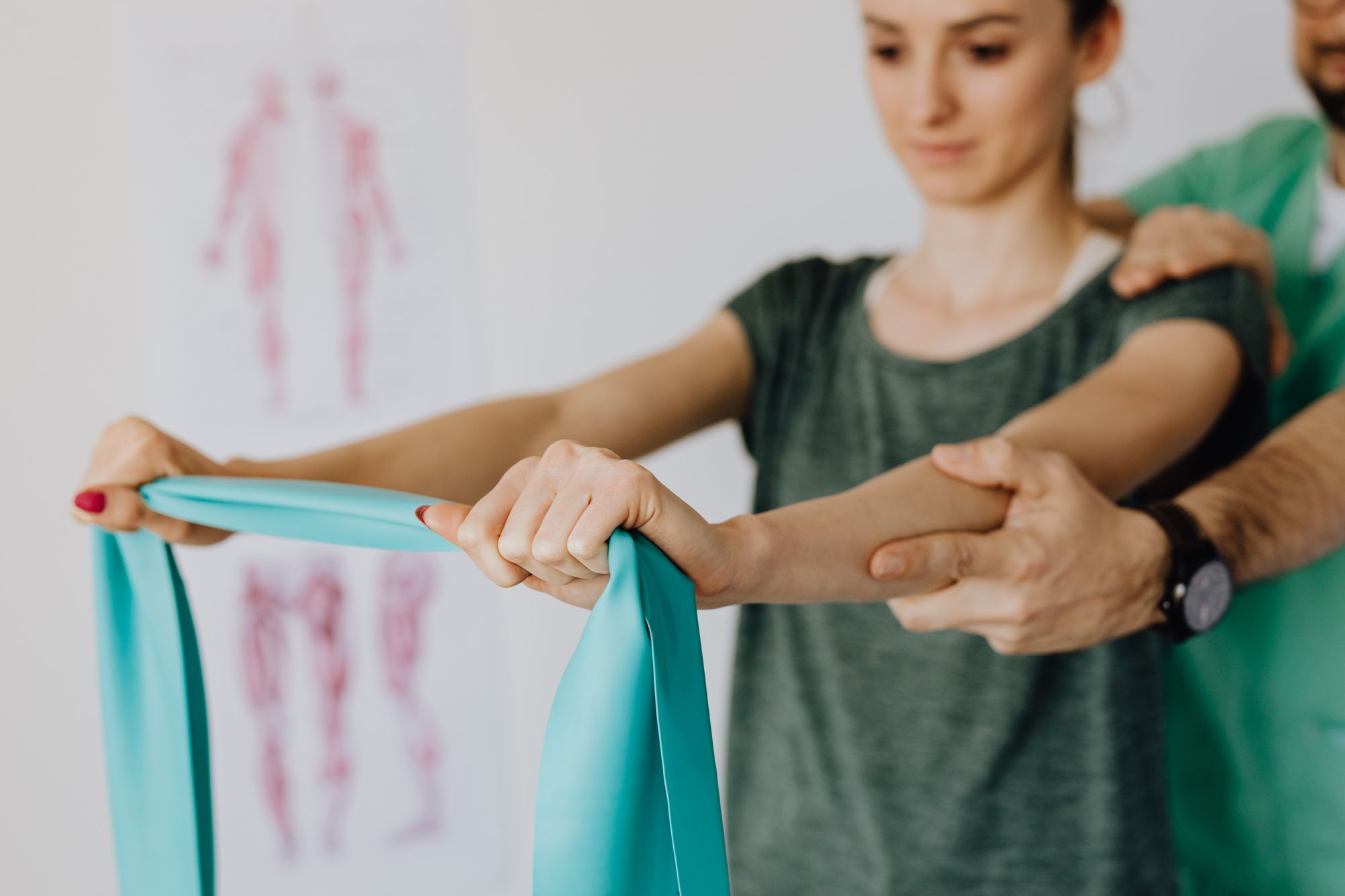 A physio guiding a patient's arms through a resistance band exercise