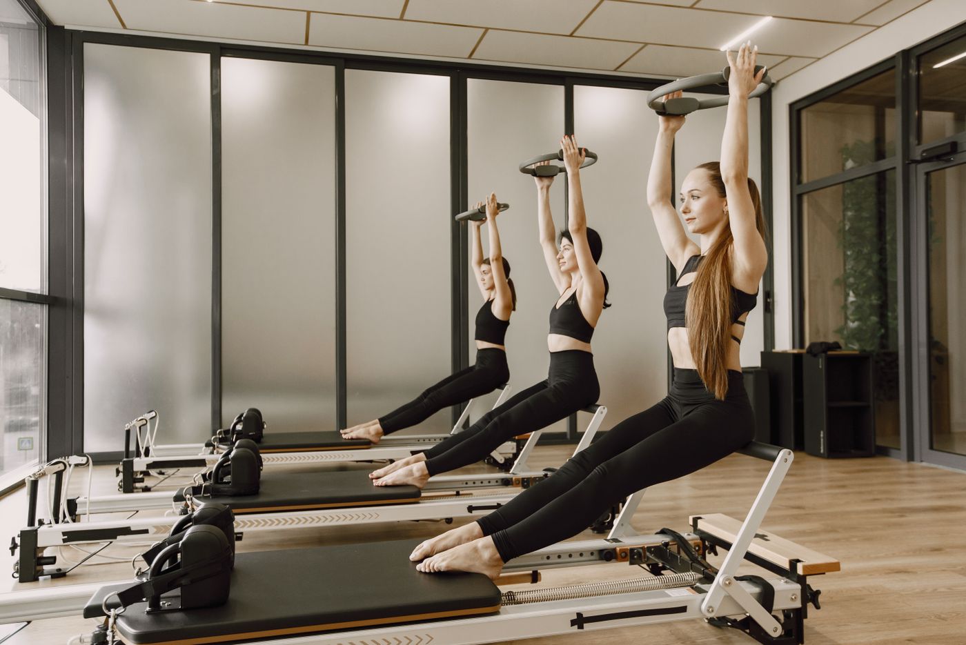 A group reformer class lifting light weights overhead